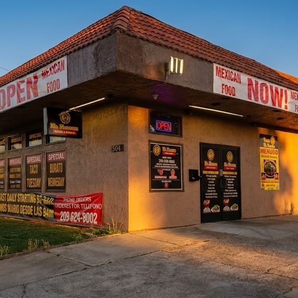 Exterior of a Mexican restaurant with "OPEN" signs, daily specials, and a parking lot at sunset.